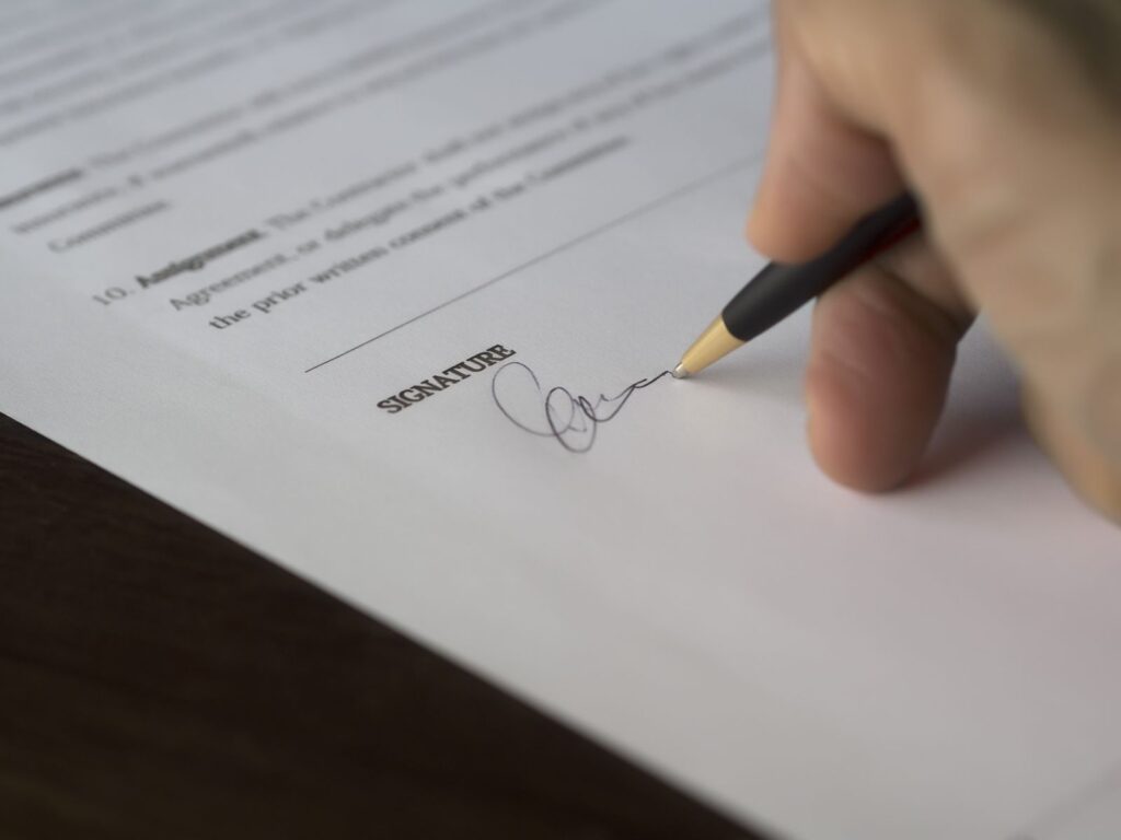 A hand signing a legal document with a fountain pen